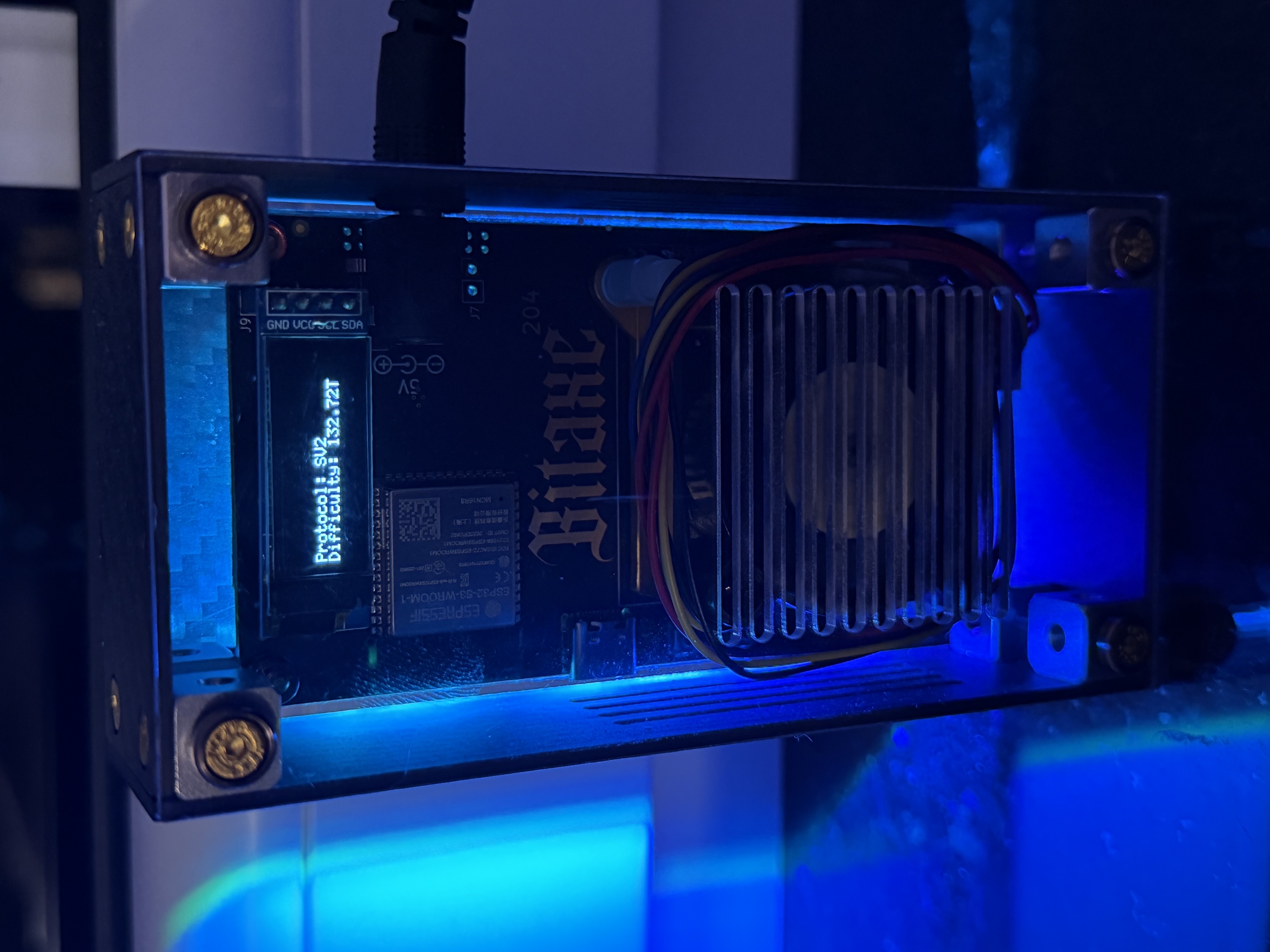 My blue-lit Bitaxe Ultra in a clear acrylic case, its display showing Protocol: SV2